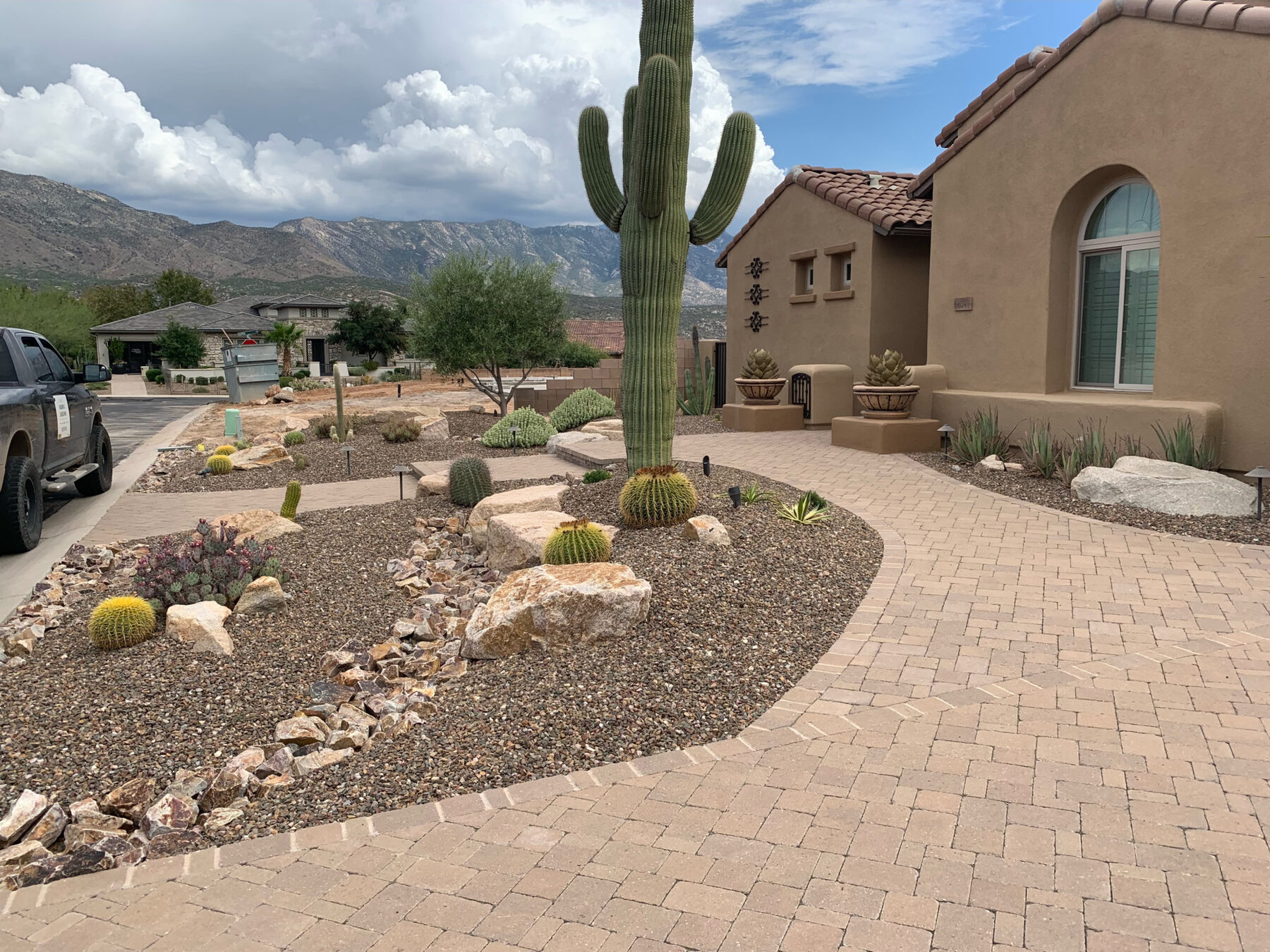 Curved paver walkway bordered by gravel, boulders, cacti, and landscape lighting