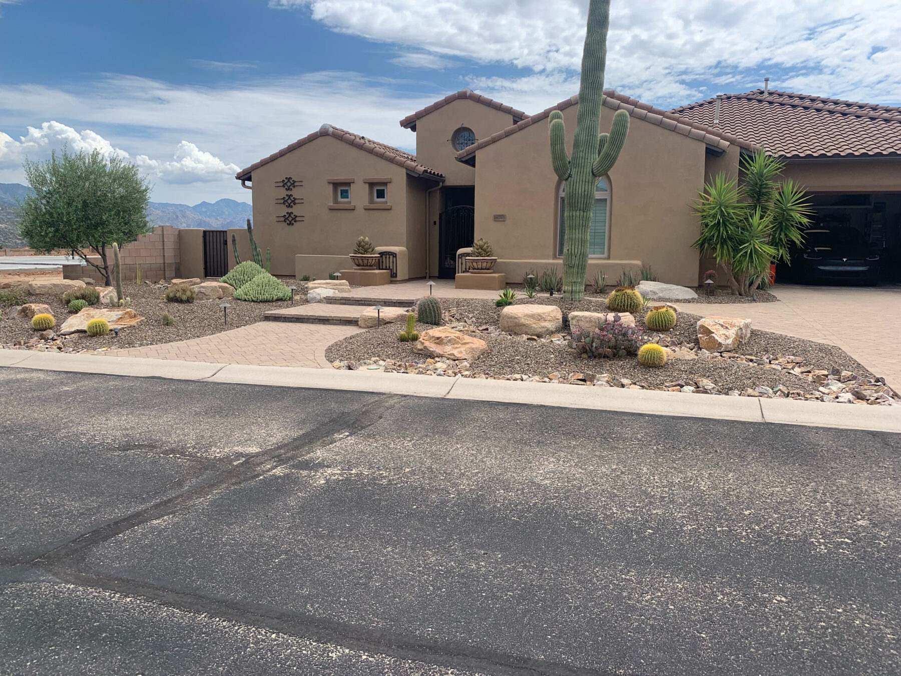 Wide view of a completed curved paver driveway with desert landscaping and stone accents